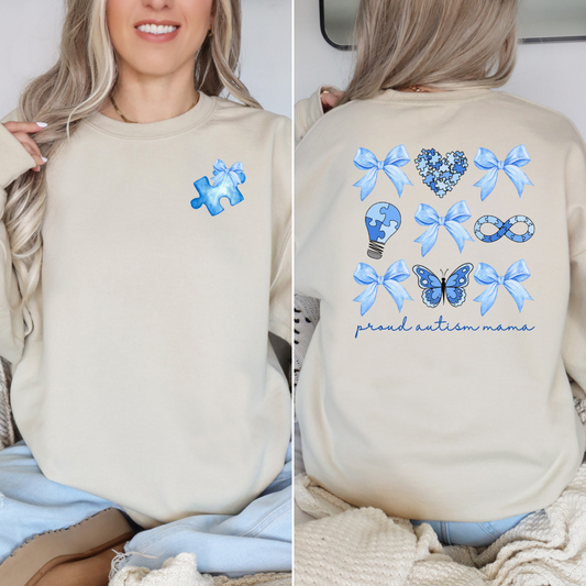 Sand colored sweatshirt with a soft blue puzzle piece  with a bow on the left chest. On the back blue bows and Autism pieces in a Coquette style that says proud autism mama