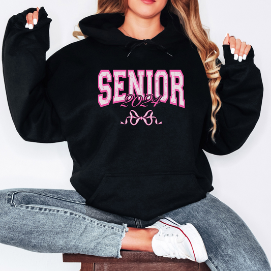 Black hoodie with Senior 2024 on the front in pink writing with a pink bow